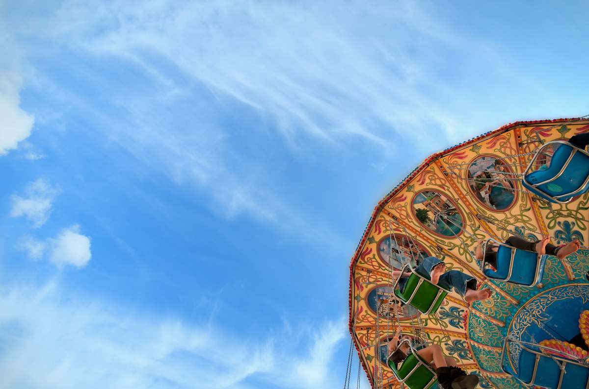 sky low angle photo of brown, green, and blue carousel under cloudy sky blue